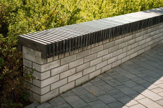 Wooden bench with slat seat on concrete block retaining wall in garden  
