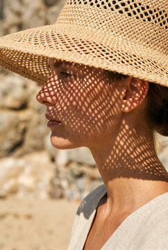 Woman in straw hat with geometric shadows. Summer fashion