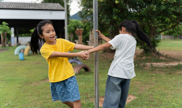 Happy children playing together on a school playground, holding hands and spinning around a pole, celebrating friendship, teamwork, active lifestyle, outdoor fun and healthy childhood development.