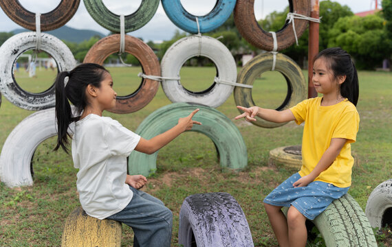 Happy children playing rock paper scissors on a colorful playground, enjoying friendship, teamwork, communication, decision making, outdoor fun and healthy childhood development