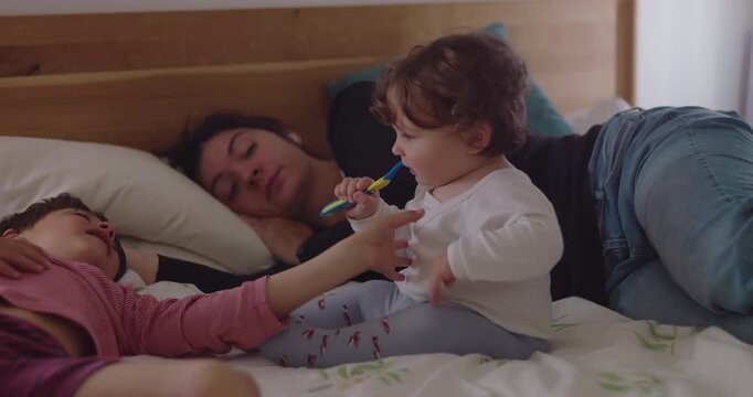 Older brother pushes toddler during rough-and-tumble play on bedroom bed as younger sibling regains balance, showing resilience, sibling boundaries and authentic family dynamics