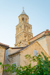 Fototapeta premium Low angle of Saint Domnius Bell Tower above stone houses in Split, Croatia. Historic Romanesque architecture under clear sky in Diocletian's Palace.