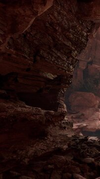 Rocks form high walls in a narrow canyon. Sunlight filters through, creating shadows on the ground. The scene shows natural layers and textures of the stone around noon.