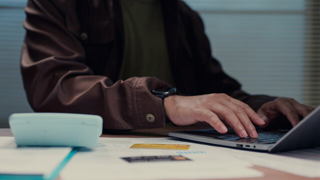 Dedicated worker typing laptop keyboard office desk reviewing financial records' calculator managing corporate budget calculating operational expenses commercial enterprise administration planning.