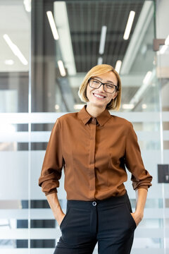 Happy business professional standing confidently in a contemporary office setting, portraying leadership and success while looking at the camera