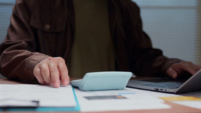 User calculates budget tax finance investment revenue cost money management desk laptop paper document office professional job workplace economy market analysis strategy plan track audit expense.