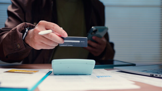 Customer holding credit card mobile phone calculating budget expense payment online commerce financial transaction shopping office desk workspace billing invoice accounting corporate management.
