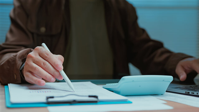 Business person analyzing financial documents holding stylus reviewing corporate budget data calculating expense report planning investment strategy management workflow office desk professional.