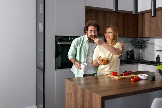 Couple enjoys cooking together in modern kitchen while sharing food and smiling