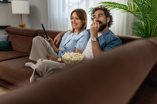 Couple enjoying a movie night at home with popcorn in a cozy living room
