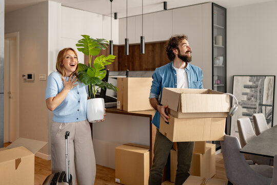 Couple moving into new home and unpacking boxes with excitement in bright living room