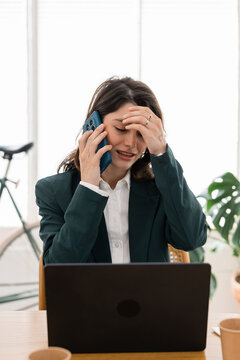 Stressed business woman talking phone having headache