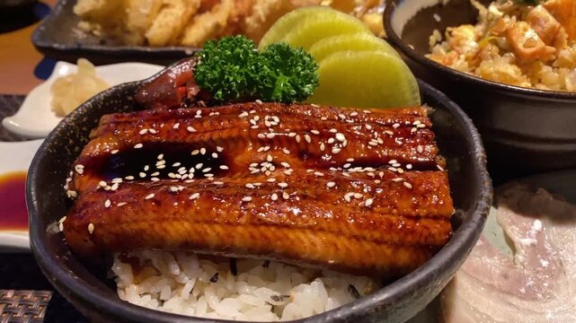 Video of authentic unadon featuring glazed grilled eel over steamed rice with traditional Japanese accompaniments.