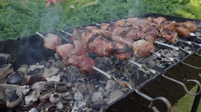 Delicious pork shashlik skewers grilling over hot charcoal on metal brazier outdoor barbecue picnic