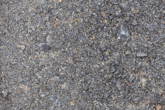 Close-up view of rough asphalt road texture background. Blacktop pavement surface texture, street construction material, and tarmac highway backdrop.