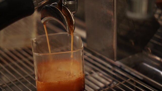Fresh espresso flows directly from a professional coffee machine into a glass container. Precision brewing highlights specialty coffee craftsmanship and modern cafe culture