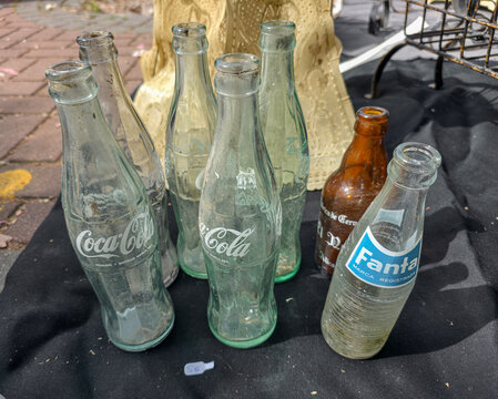 Xalo, Spain - June 20, 2026.Collection of dusty vintage glass beverage bottles including Coca Cola and Fanta displayed at a street market