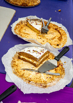 Layered sponge cake with white frosting and dried flower petals on baking parchment