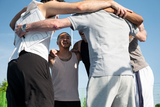 Basketball players and coach huddling, smiling, showing unity and teamwork