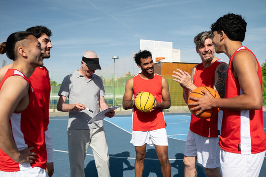 Basketball coach explaining game strategy to diverse team on outdoor court