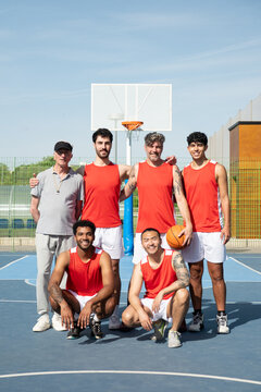Diverse basketball team and coach smiling together on an outdoor sports court