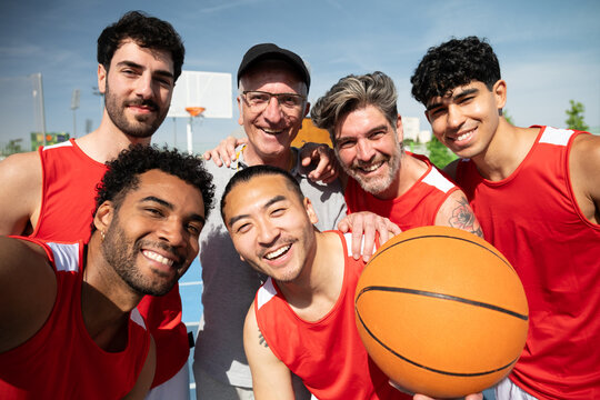 Happy men of different ages and ethnicities posing for a selfie on a basketball court