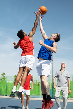 Two athletes leaping to dispute a basketball on an outdoor court
