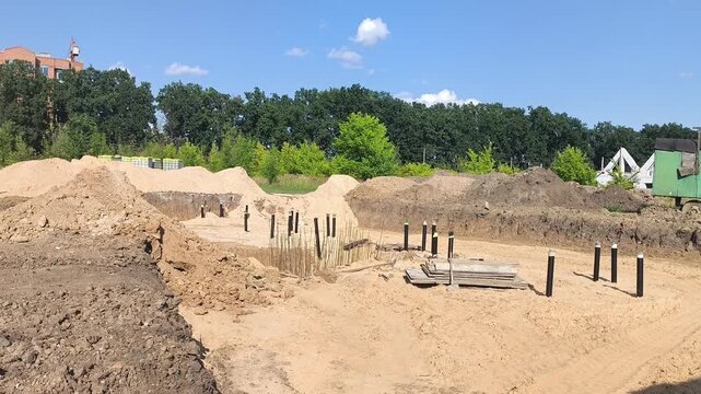 Summer construction site with a large excavation pit, underground utility pipes laid in sand and piles of construction sand. Infrastructure development and engineering works. 