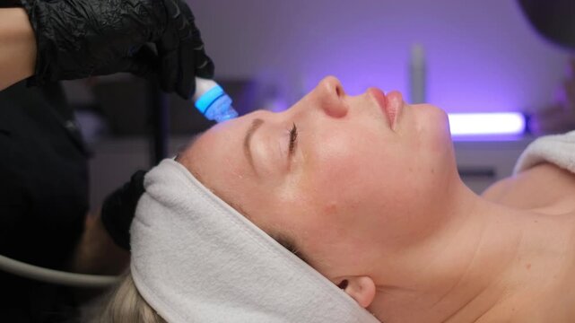 Professional beautician performing a rejuvenating hydrafacial procedure on a client's face. Modern cosmetology for skin cleansing and anti-aging care
