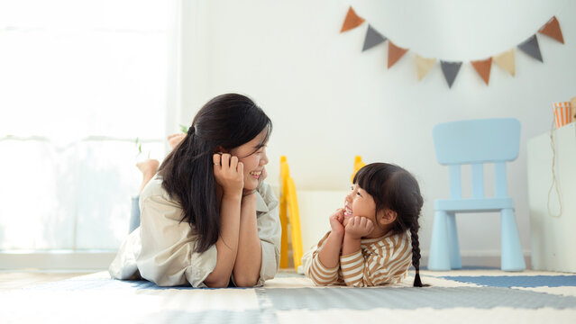Mom and Girl Spend Time Together on the Floor in a Bright Room With Colorful Decorations