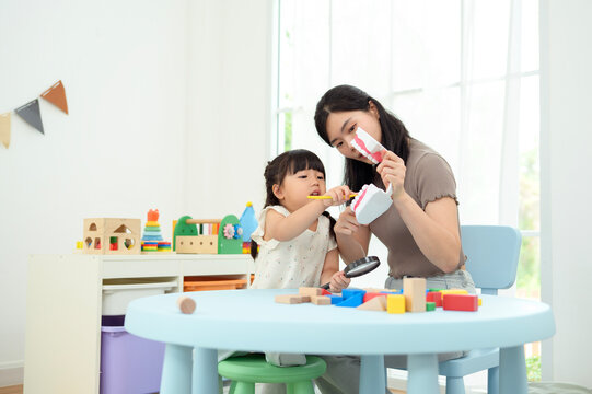 Girl and Mom Work Together on a Fun Activity at Home While Learning to Brush Teeth