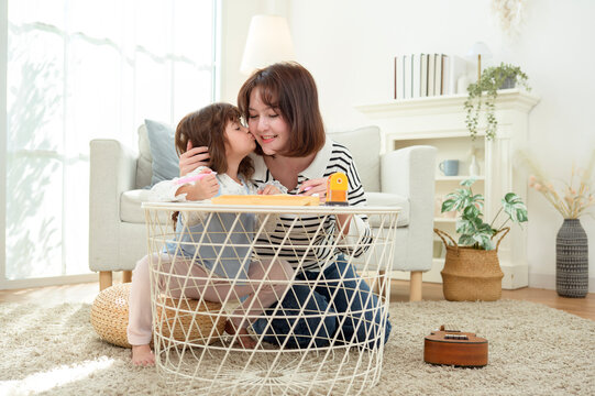 Mom Helps Daughter With Homework in a Bright Living Room on a Sunny Day