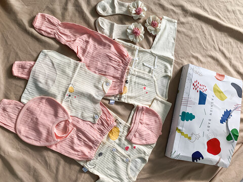 Medan, Indonesia - September 12, 2023: Collection of cute newborn baby clothes rompers and onesies arranged flat lay on soft fabric background