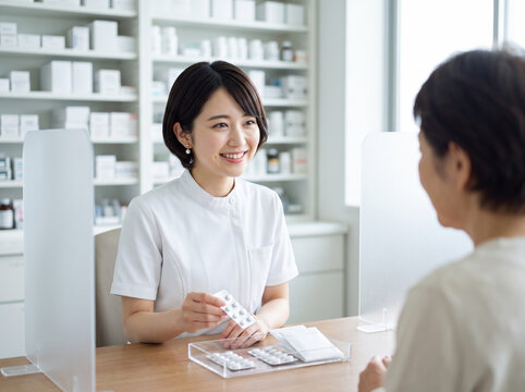 カウンターテーブル越しに処方薬を提示する笑顔の薬剤師の女性