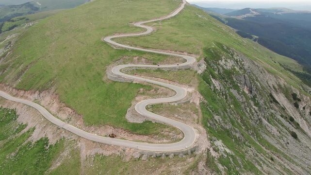 Aerial tracking shot of two motorcycles descending the Transalpina hairpin turns in the Romanian Carpathians