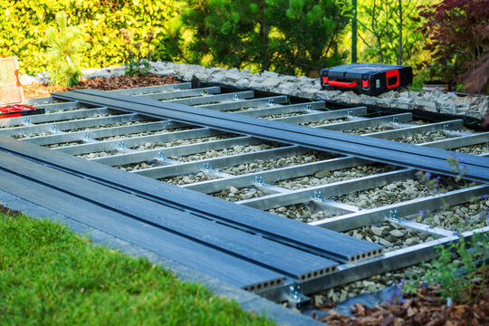 Construction of a deck frame in a backyard with rocks and tools present