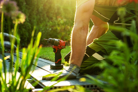 Gardener uses a drill in the backyard during the late afternoon