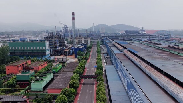 Aerial view of heavy industrial factory complex under gloomy overcast sky. Ideal for manufacturing, climate change, and logistics concepts.
