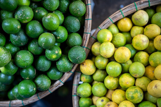 Street food market selling various kinds of citruses, baskets filled with fresh ripe green and yellow limes on sale, raw lime fruits selling at bazaar, organic exotic produce offered from farmers.