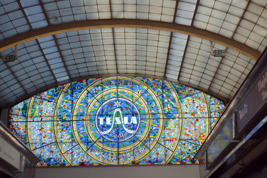 PRAGUE, CZECH REPUBLIC - JUNE, 29, 2026. Colorful stained glass dome window with tesla Radio logo and radial mosaic pattern in a historic arcade for market interior background and travel banner