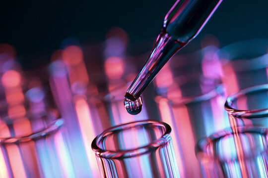 Close Up of Pipette Dispensing Liquid into Laboratory Test Tube with Neon Lighting