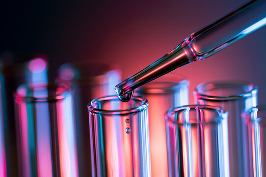 Close Up of Pipette Dispensing Liquid into Laboratory Test Tube with Neon Lighting