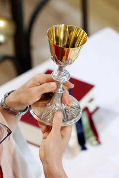 A priest celebrates the Eucharist, holding a golden chalice during a Mass at the Sanctuary of the Blessed Fountain. Eucharistic celebration.