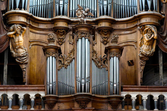 Notre-Dame Collegiate Church. A monumental organ made of carved wood with metal pipes, a cherub, and statues of human figures.