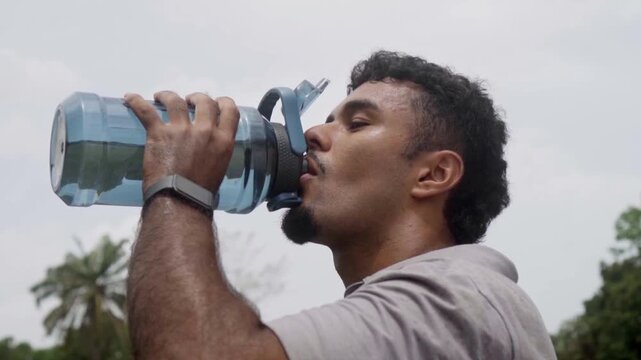 Sweaty athlete drinking water after outdoor workout