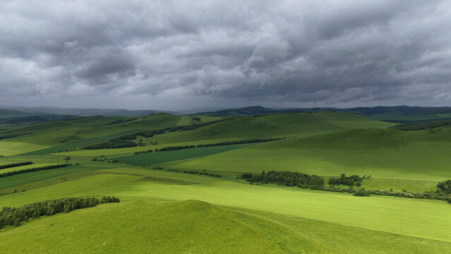 Aerial view of rolling farmland under dramatic clouds in Hulunbuir, Inner Mongolia