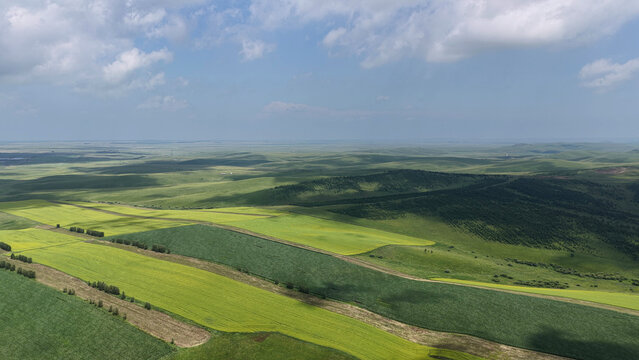 Aerial view of rolling farmland under dramatic clouds in Hulunbuir, Inner Mongolia