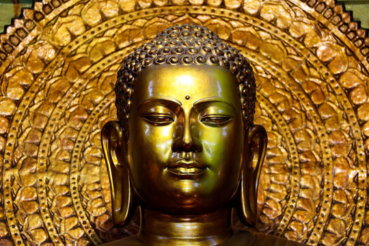 Xa Loi Pagoda. Gilded bronze statue of Sakyamuni Buddha: crown, elongated ears, an expression of absolute equanimity, and a halo with a double ring of chiseled petals. Ho Chi Minh City, Vietnam.