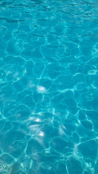 Crystal clear swimming pool water with turquoise ripples and sunlight reflections
