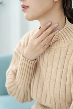 Asian woman put on neck due to a sore throat. female tonsillitis causes a inflammation. treated by taking water, taking antibiotics, consult a doctor, virus, corona virus, Influenza, flu